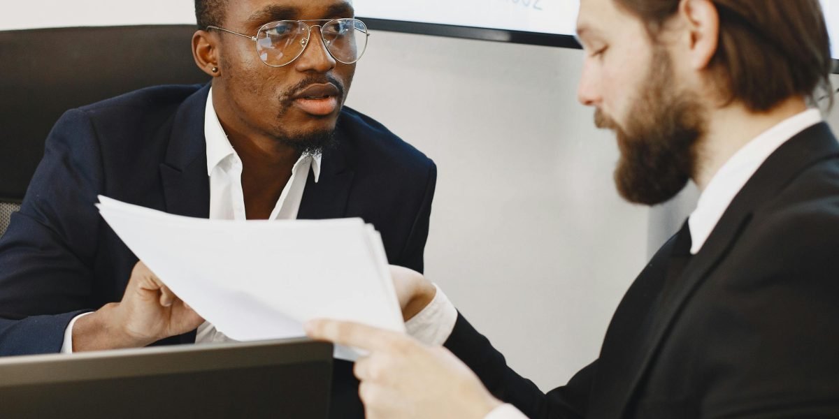 Two professionals engaged in a discussion about luxury real estate trends, possibly a client and an agent.