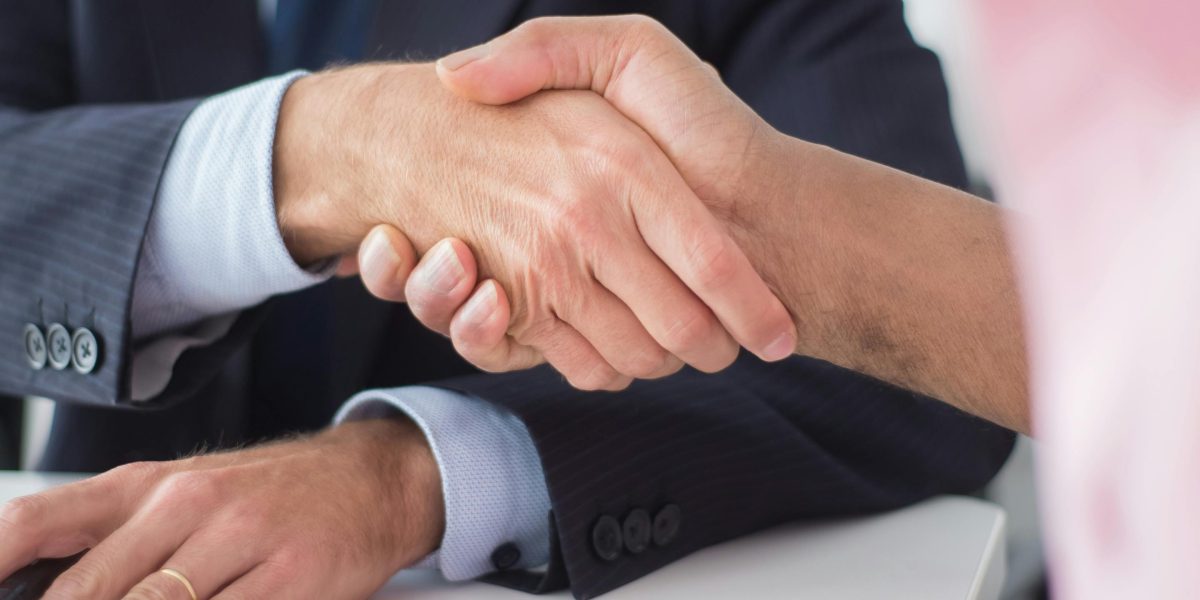 Two professionals shaking hands, symbolizing a successful and legally sound business agreement.