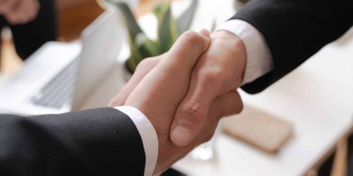 Two professionals shaking hands, signifying a successful property transaction or partnership for international investors.