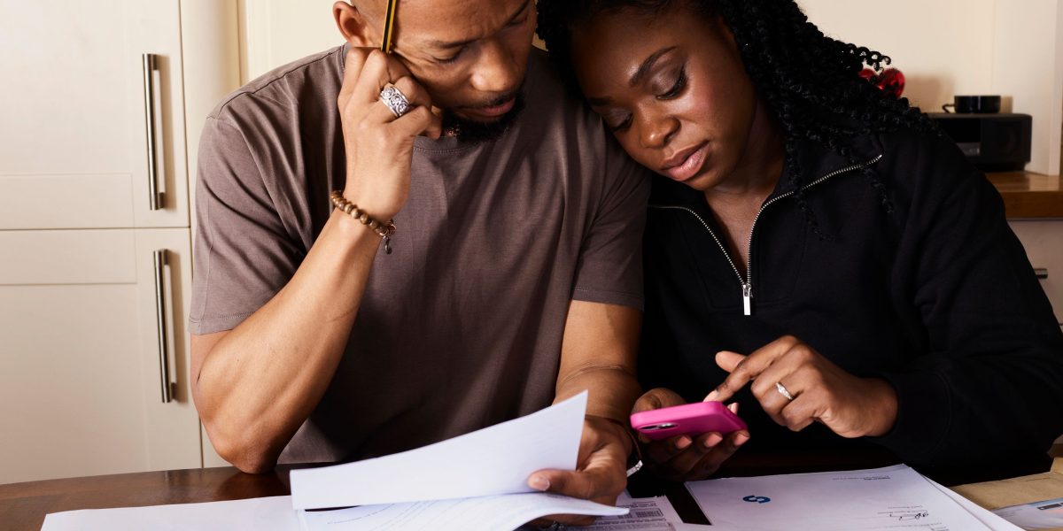 A couple carefully examining financial documents and plans, symbolizing the importance of budgeting and investment strategy.